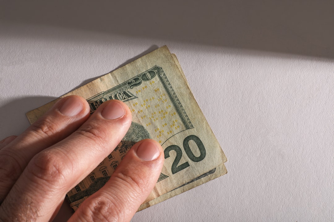 A hand holding a twenty dollar bill.